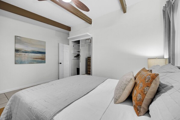 Un dormitorio con una cama grande, un vestidor y un cuadro en la pared.