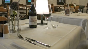 Une table à manger dressée avec une bouteille de vin, des verres et des couverts.
