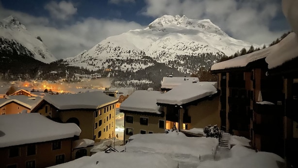 Une montagne enneigée, avec une ville au premier plan.