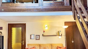 Un salon comprenant un canapé, une table basse en verre, un luminaire fixé au mur et un escalier.