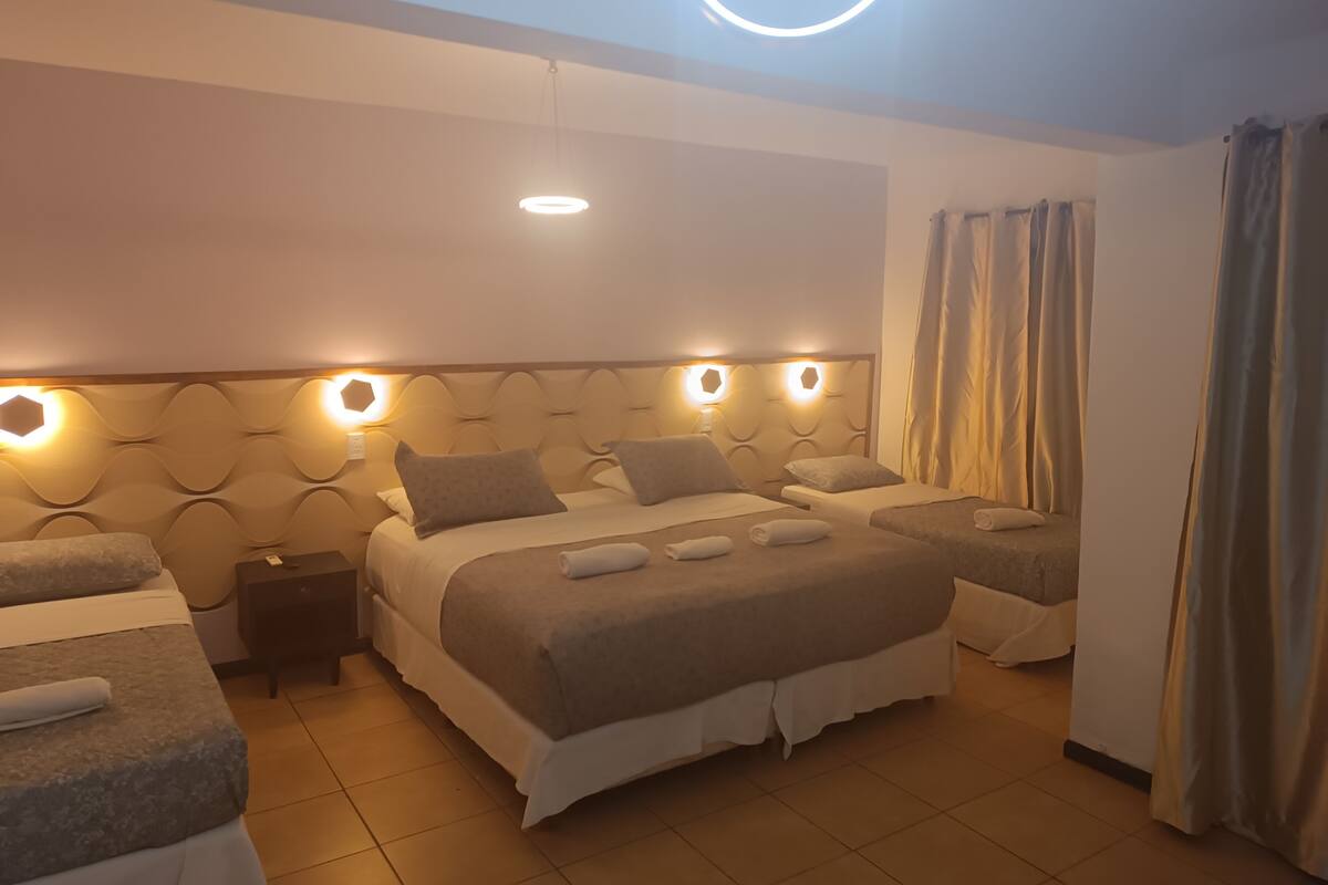 A hotel room with a large bed, two bedside tables, and a circular light fixture on the ceiling.