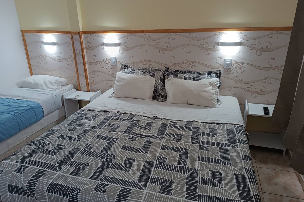 A hotel room with two beds, a patterned bedspread, and a decorative headboard.