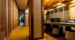 Un couloir aux murs lambrissés, un comptoir équipé d’appareils électroménagers et une vue sur une pièce dont le plafond est en bois.