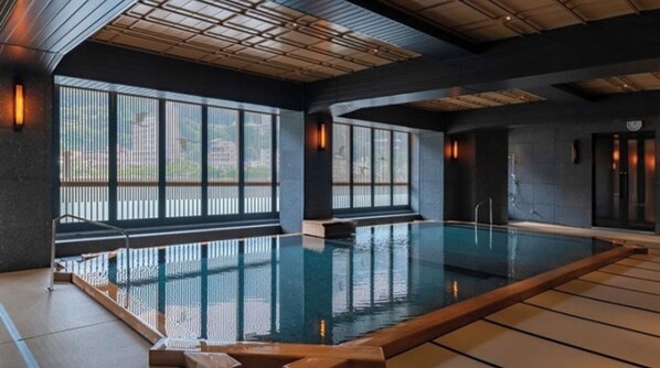 Une piscine avec vue sur l’extérieur, de grandes fenêtres et un aménagement intérieur moderne.