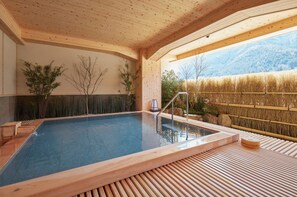 Une piscine intérieure en bois, avec vue sur les montagnes, entourée d’une clôture en bambou et dotée d’une terrasse en bois.