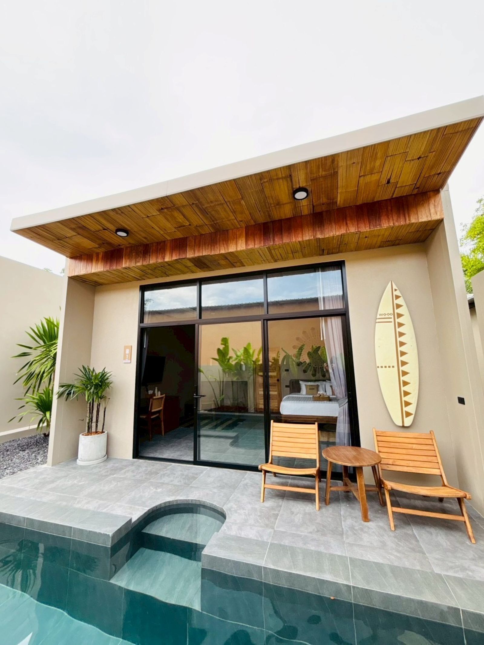 Een modern gebouw met een zwembad, houten terras en een surfboard decoratie.