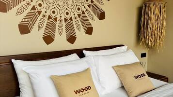 A neatly made bed with white and beige pillows, a decorative wall mural, and a woven hanging light fixture.