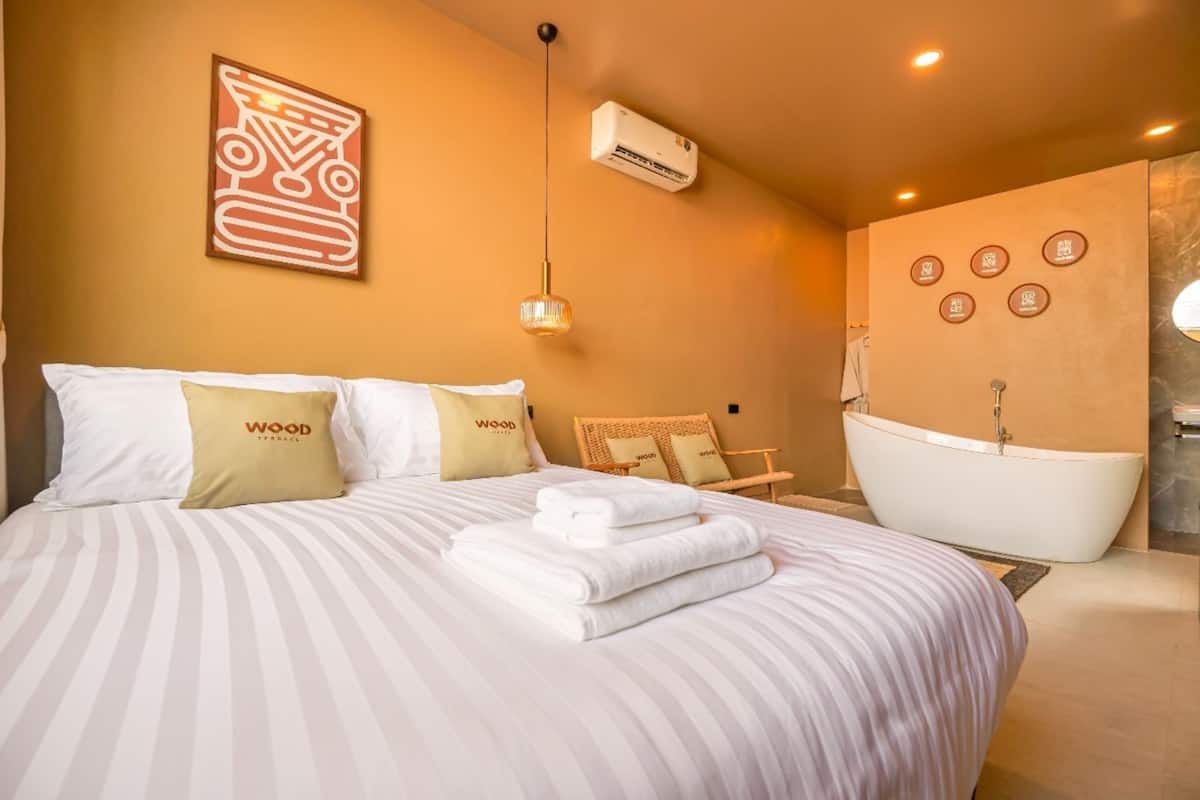 Une chambre d’hôtel avec un grand lit, une baignoire et un climatiseur fixé au mur.