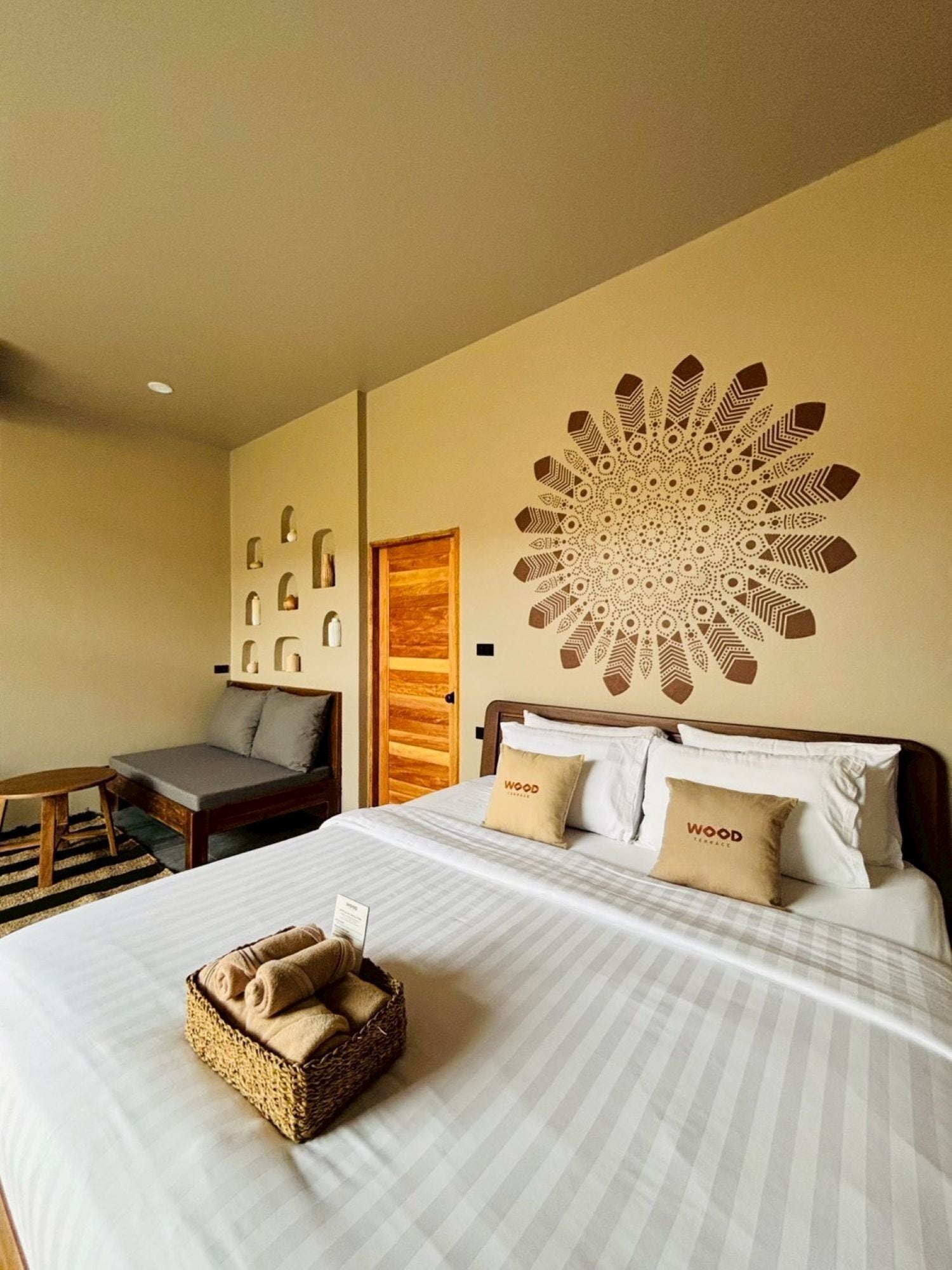 A hotel room with a large bed, a wooden headboard, and a decorative wall piece.