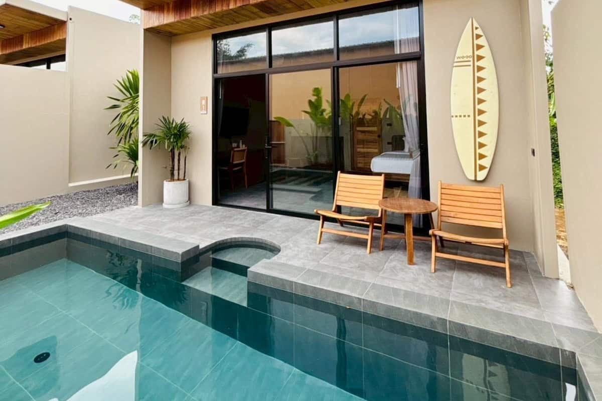 Une maison moderne avec une piscine, un plafond en bois et une planche de surf accrochée au mur.