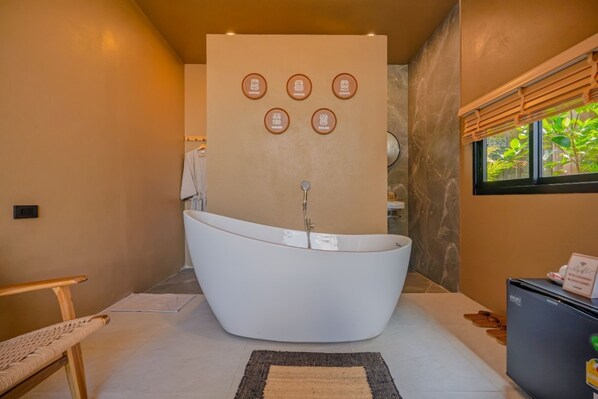 A modern bathroom with a freestanding bathtub, a wooden bench, and a wall-mounted towel rack.