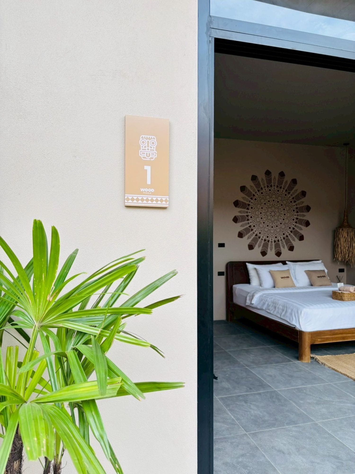 A modern bedroom with a large bed, a decorative wall piece, and a potted plant.