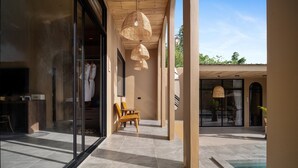 Un espacio exterior moderno con piscina, mobiliario y una puerta de vidrio que da a una habitación.