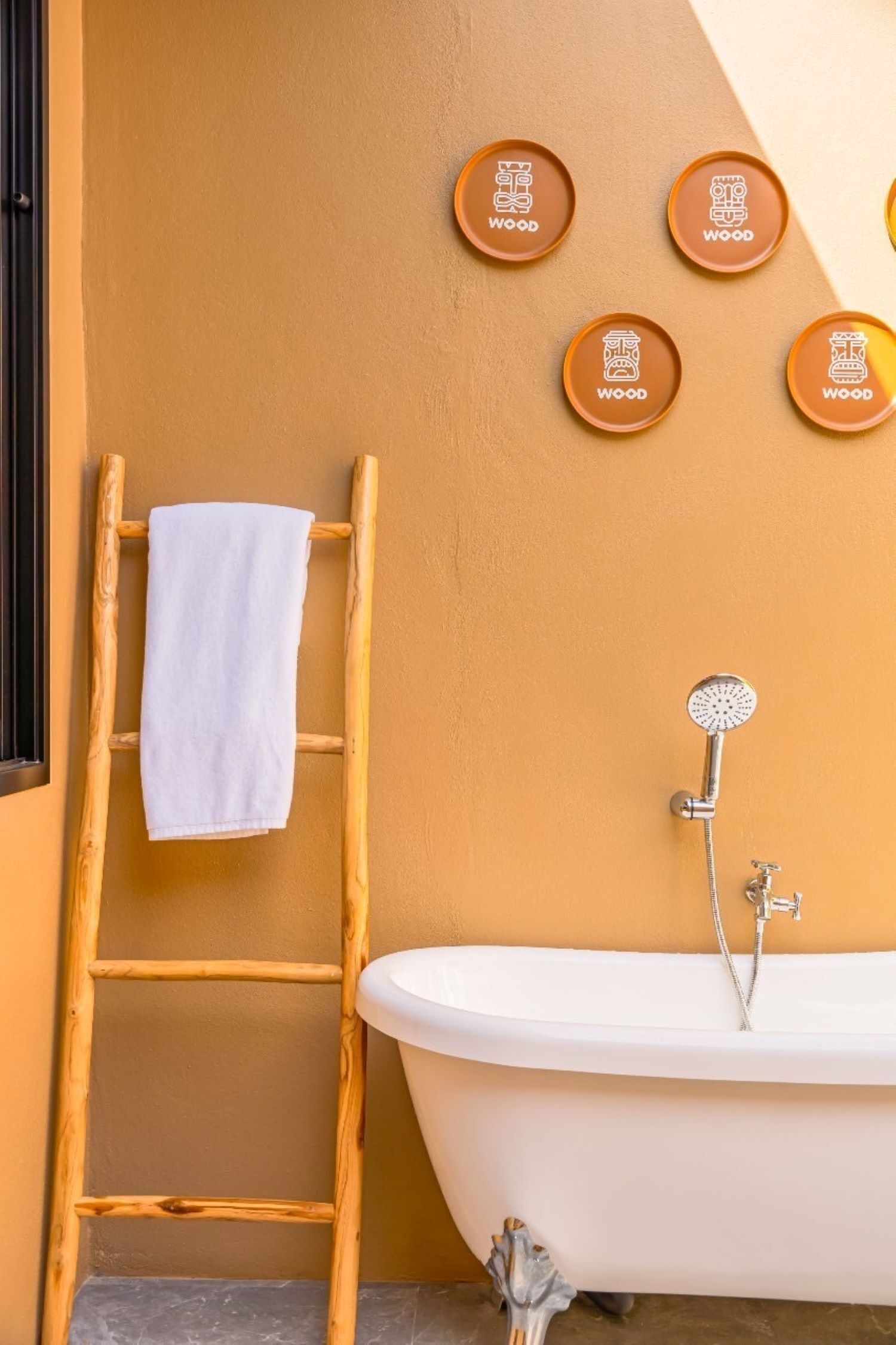 A bathroom with a white bathtub, a wooden ladder, and four wooden wall-mounted buttons labeled "WOOD".