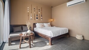 Un dormitorio con cama, sofá, una mesita y detalles decorativos en la pared, además de un aire acondicionado.