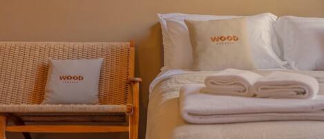 A hotel room with a bed, a wicker chair, and a wall-mounted air conditioner.