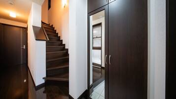 A modern interior with a dark wooden staircase, a glass door with a window, and a light fixture on the wall.