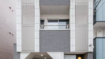 A modern building with a central entrance, two balconies, and a covered area.