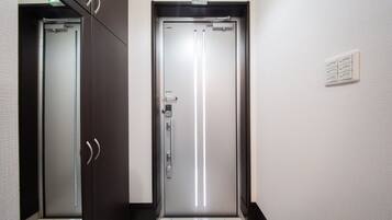 A hallway with two doors, one with a green emergency exit sign above it.