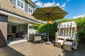 An outdoor patio with a table, chairs, and a large umbrella.