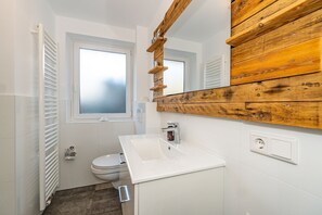 A small bathroom with a white sink, a toilet, and a window. - Lachmöwe - Holiday home in Tinnum with fireplace and terrace. (Sylt / OT Tinnum)