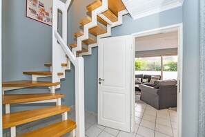 A staircase with wooden steps and white railings leading to a room with a grey sofa and a window. - Lachmöwe - Holiday home in Tinnum with fireplace and terrace. (Sylt / OT Tinnum)