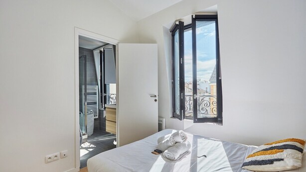 Un dormitorio con cama, ventana, puerta y vistas al exterior.