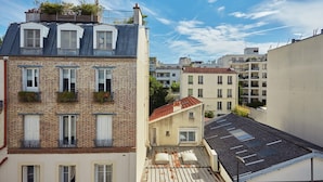 Un edificio de varios pisos con fachada de ladrillo, ventanas de tejado y balcones con plantas.