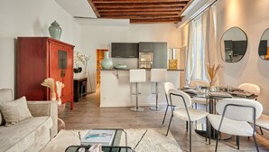 A modern living room with a sofa, a coffee table, and a dining area with chairs and a table. - Superb Parisian Apartment Center of Paris (Paris)