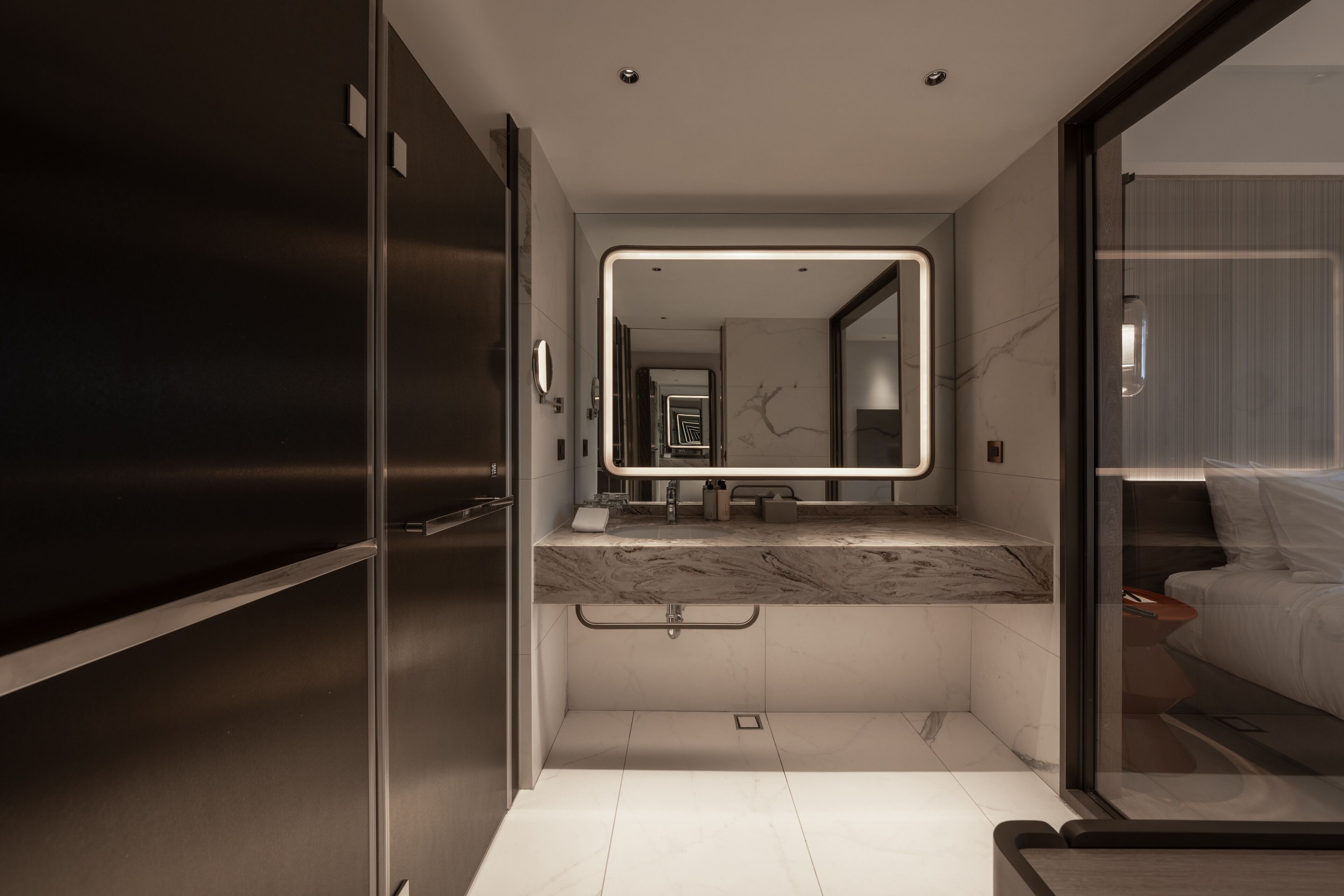 A modern bathroom with a large mirror, a marble countertop, and a separate shower area.