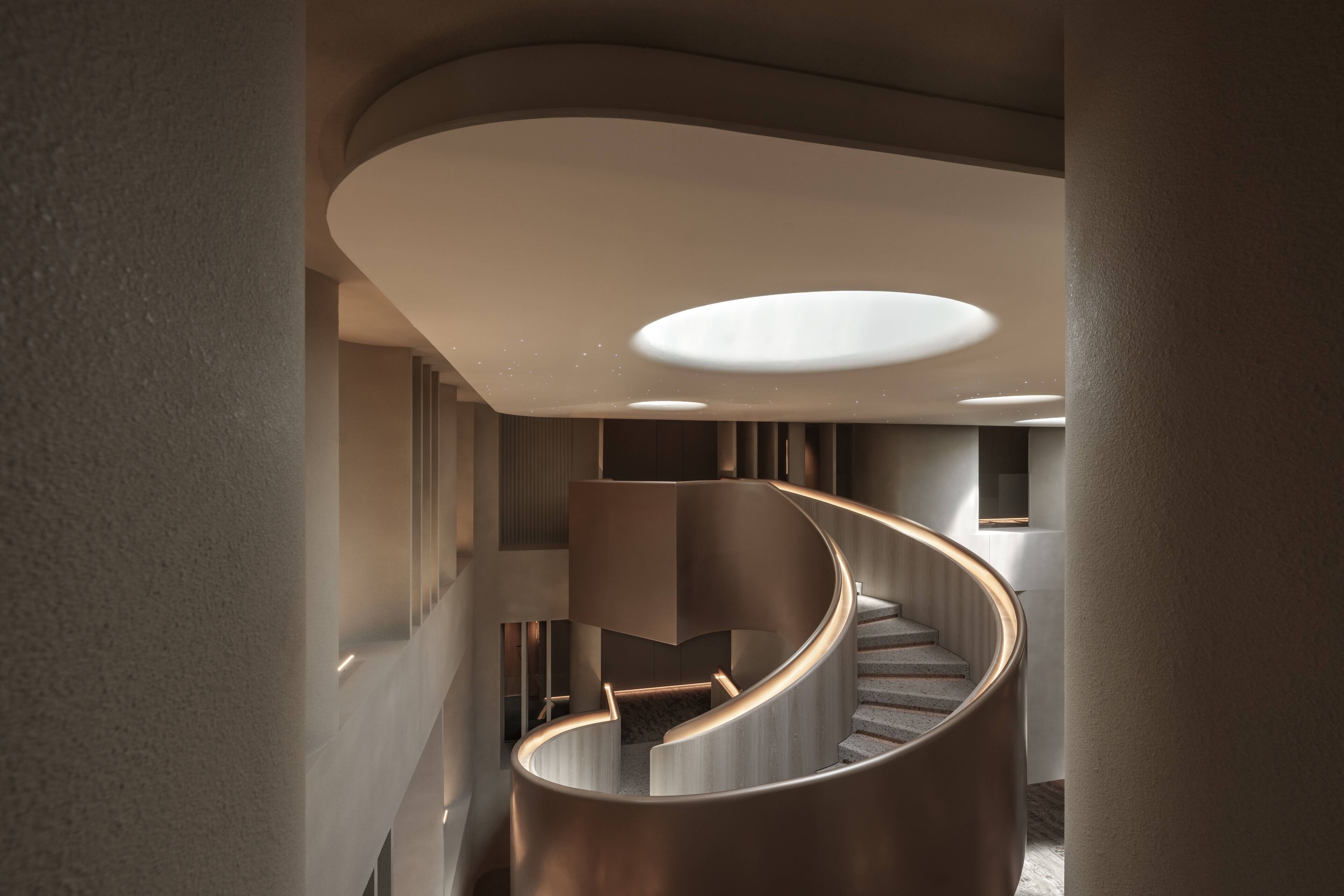 Una escalera espiral moderna con un diseño minimalista, barandilla curvada e iluminación empotrada.