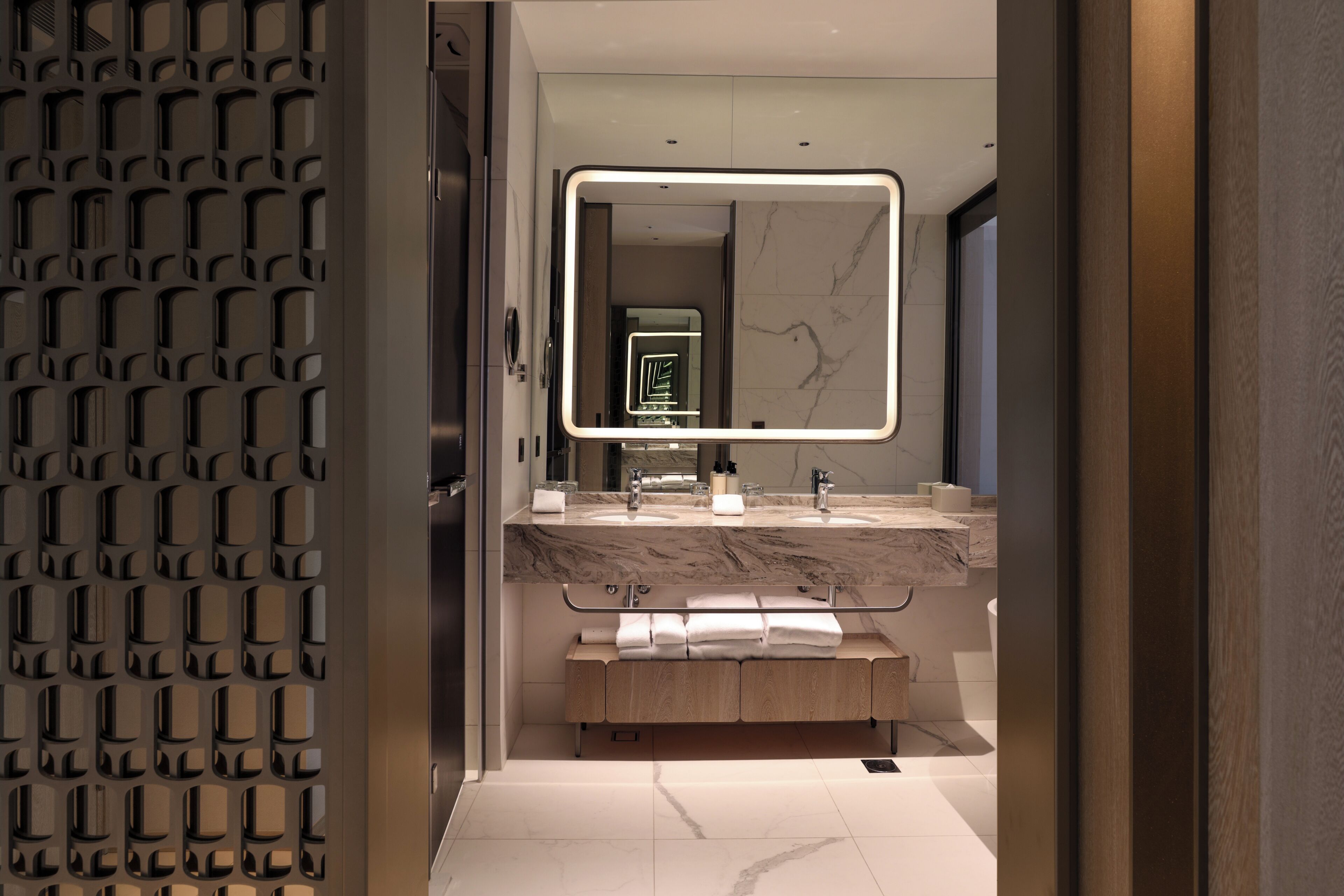 Une salle de bain moderne avec un comptoir en marbre, un grand miroir et un meuble-lavabo en bois.