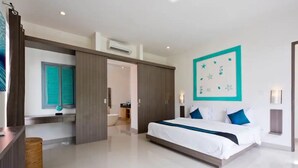 A modern hotel room with a large bed, a bathroom visible through an open door, and a wall-mounted air conditioning unit. - 6BR Del Mar Villas W/2 Pool near Seminyak Beach (Seminyak)