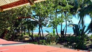 Vista de una playa con palmeras y una estructura de techo rojo.
