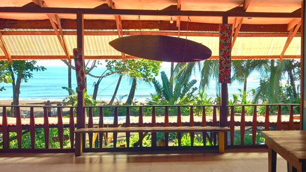 Un espacio de estar al aire libre cubierto con vista a la playa y al océano.