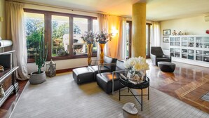 A spacious living room with a large window, a fireplace, and a dining area with a glass cabinet. - Villa Il Guscio by Interhome (Terranuova Bracciolini)