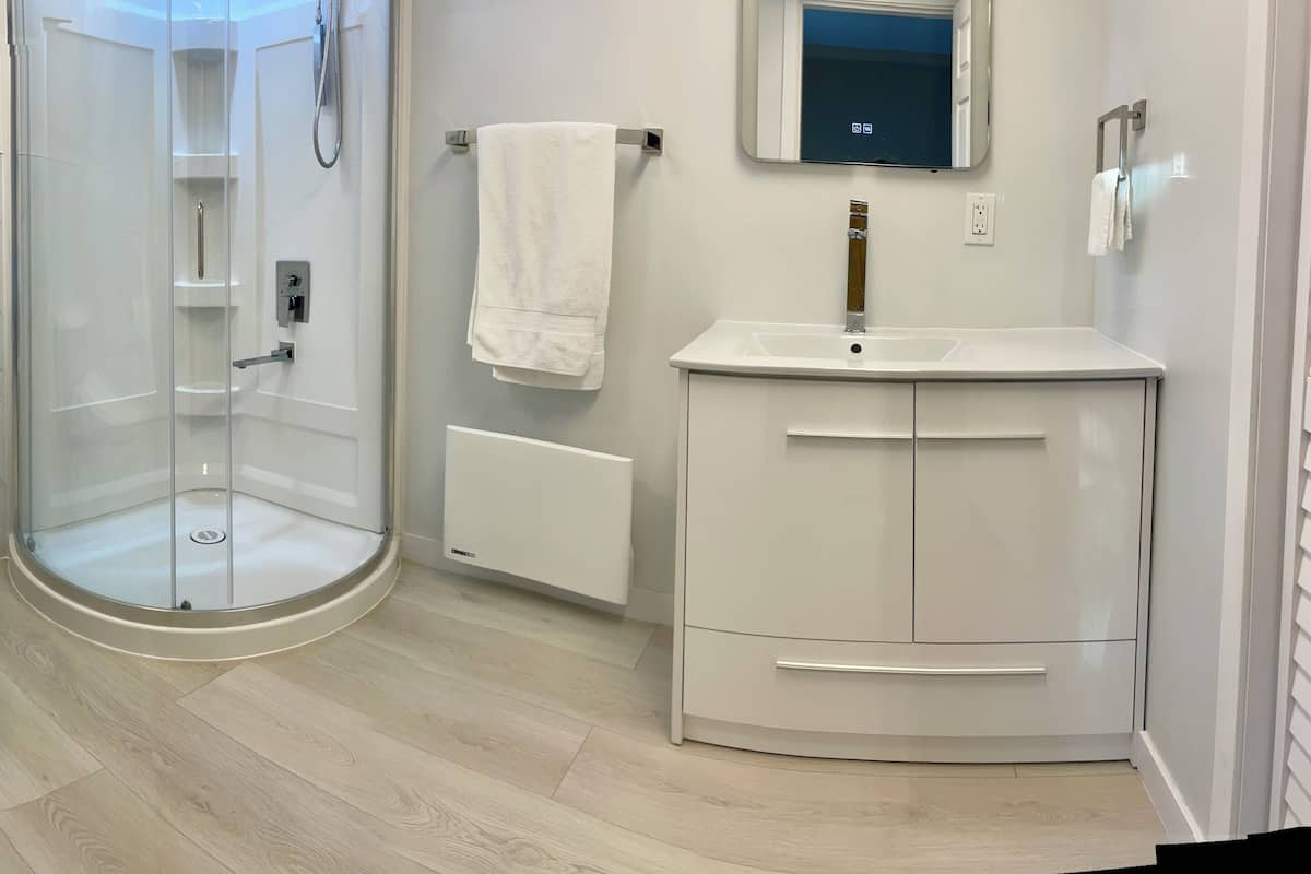 Ein modernes Badezimmer mit Duschkabine aus Glas, Toilette, Waschbecken und einem Schrank.