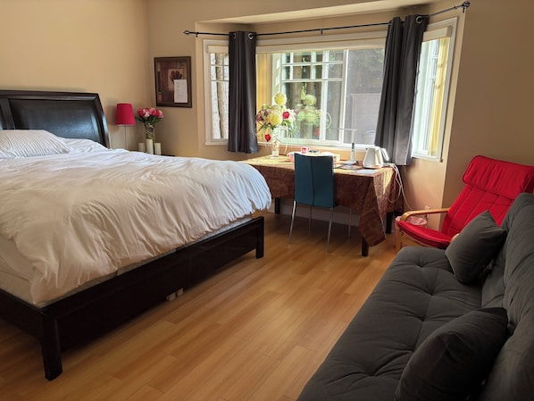 A bedroom with a large bed, a desk with a chair, a red chair, and a sofa. - Rose Garden Vancouver Airport-Richmond BC (Richmond)
