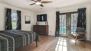 Een slaapkamer met een bed, een dressoir, een televisie en een stoel.