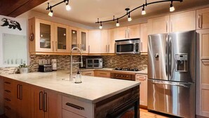 Une cuisine moderne avec des meubles en bois, un réfrigérateur en acier inoxydable, un four à micro-ondes et une cuisinière à gaz.