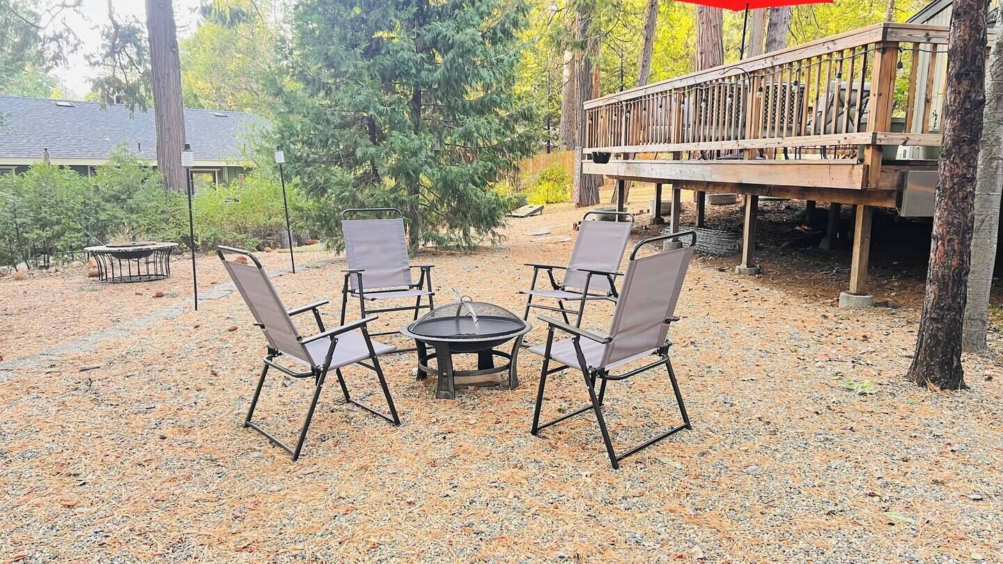 An outdoor seating area with a round table and four chairs, surrounded by a gravel ground.