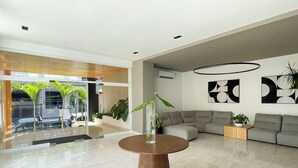 Een modern interieur met een ronde houten tafel, een grijze modulaire bank en abstracte wandkunst.