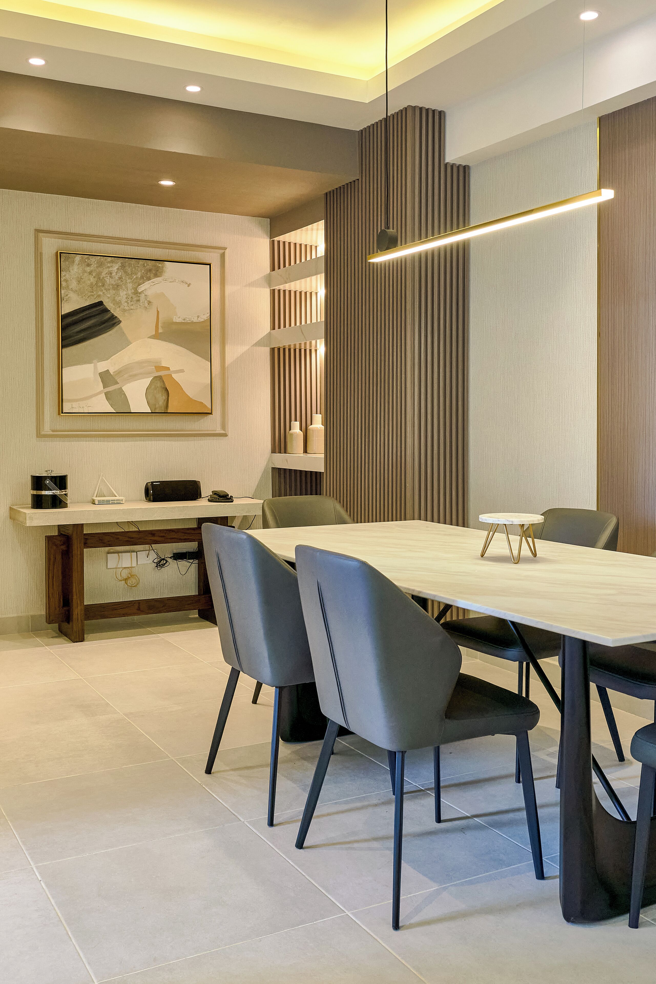 A modern conference room with a long table, four chairs, a painting on the wall, and a wooden accent wall.