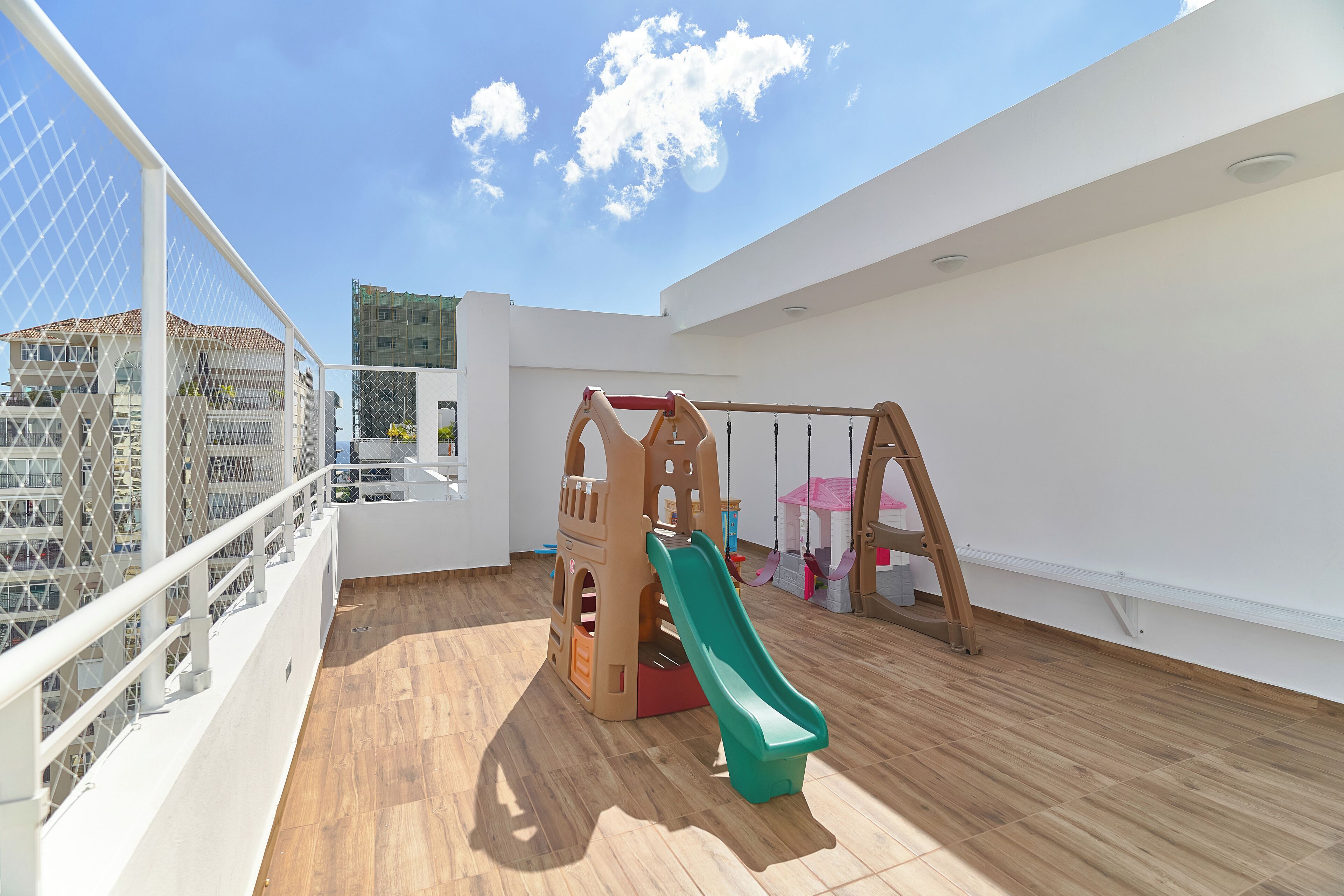 Zona de juegos infantiles con tobogán y estructura de escalada sobre un muelle de madera.