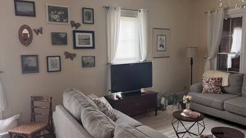 Un salon avec un canapé, un téléviseur, une table basse et un fauteuil.