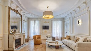 A spacious living room with a fireplace, a sofa, a coffee table, and a large mirror.