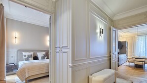 A bedroom with a bed, a bench, a wardrobe, and a television in the corner.