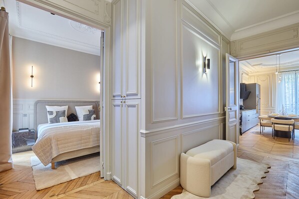 Une chambre avec un lit, un banc, une armoire et un téléviseur placé dans un coin.