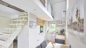 A modern kitchen with white cabinetry, a dining area with a table and chairs, and a staircase leading to an upper level. - Nice house in Zeeland near the Oosterschelde (Kattendijke)