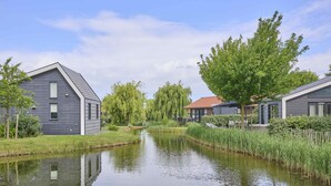 A canal with houses on either side, a clear sky, and lush greenery. - Nice house in Zeeland near the Oosterschelde (Kattendijke)